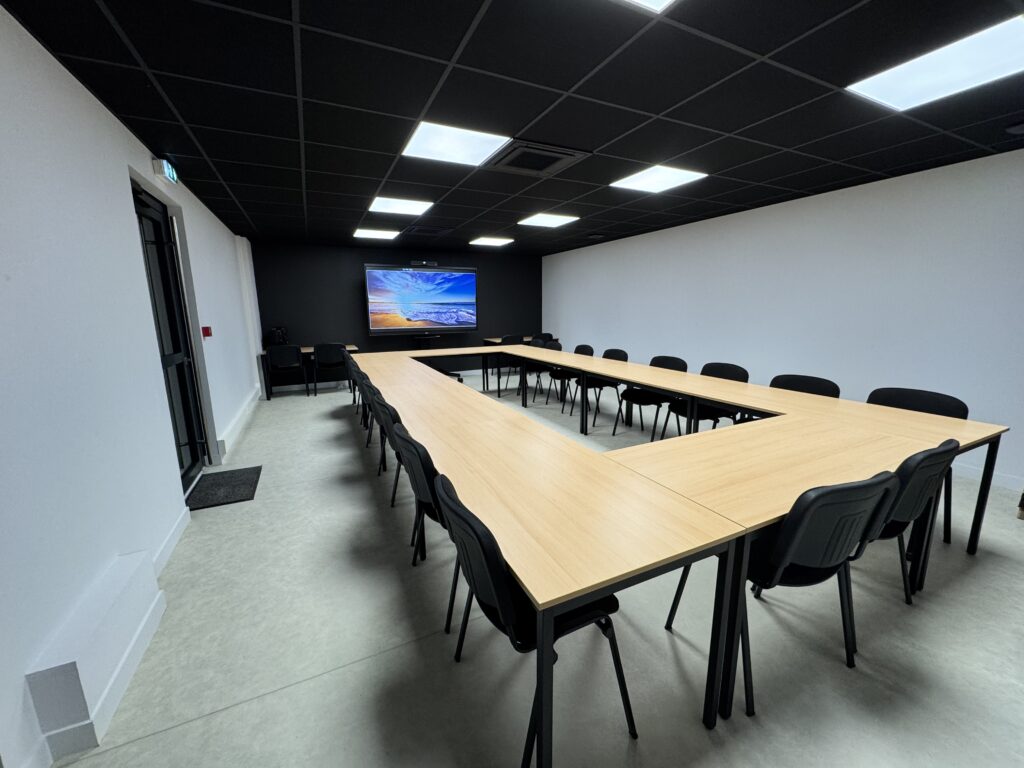 Salle de réunion avec des tables, des chaises et un grand écran